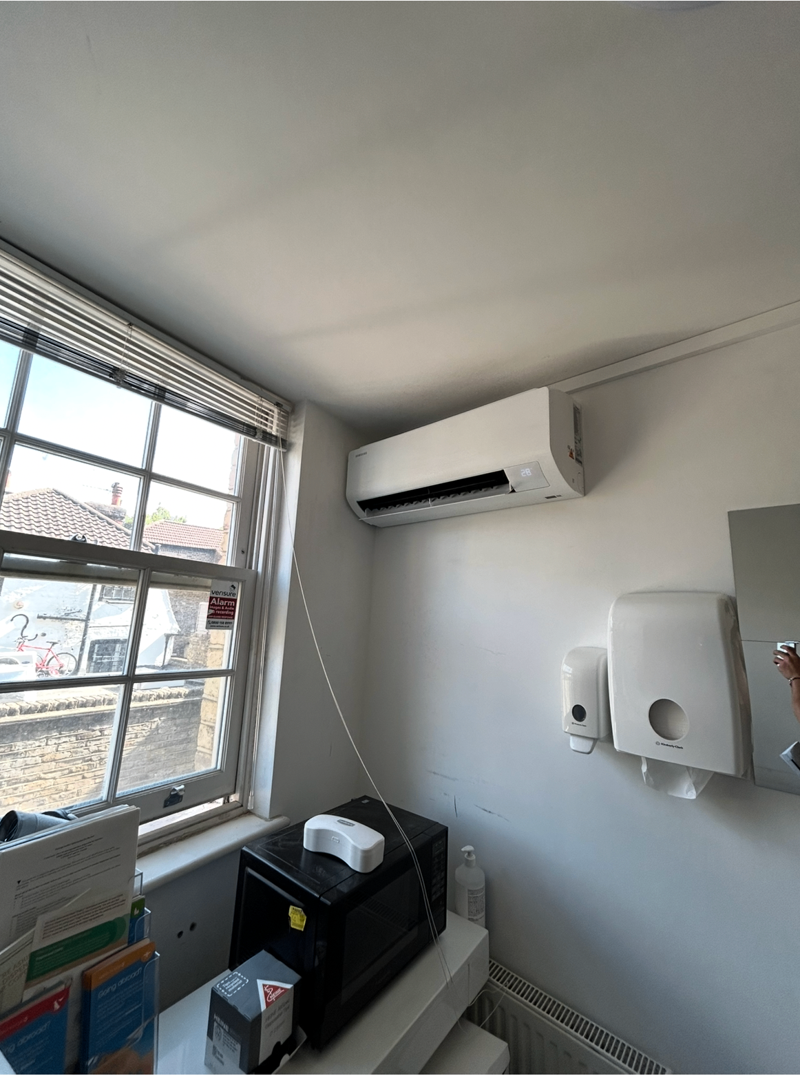 Wall-mounted AC unit installed in a clinic room beside a window